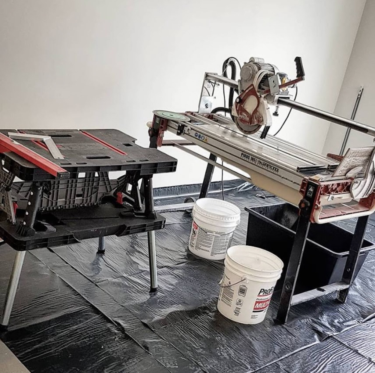 Raimondi PIKUS bridge saw set up on a real job site in Orléans — protective sheeting, Mapei thinset buckets, precision large format tile cutting by Orleans Bath and Tile
